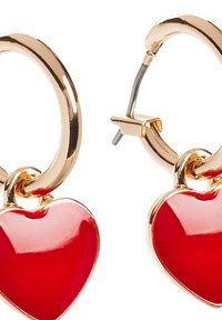 Orecchini a cerchio color oro con eleganti charms a forma di cuore rossi. I cuori hanno una texture liscia e sono saldamente attaccati ai cerchi.