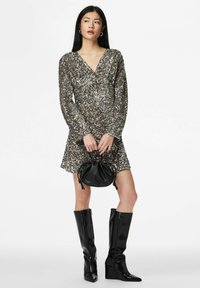 Sidabrinė blizgi ilgomis rankovėmis su V formos iškirpte, derinama su juoda odine mini rankine ir juodais kelių aukščio pleišto batais. Lygi tekstūra.