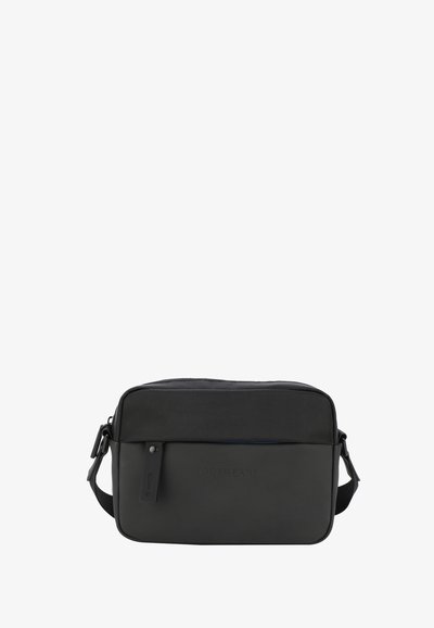 Sac messager noir avec un dessus en tissu texturé et une partie inférieure lisse, arborant un logo, une sangle ajustable et une fermeture éclair.