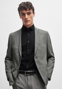 Gray patterned suit jacket over a black shirt, featuring a slim fit, notch lapels, and a single chest pocket, paired with a black belt.