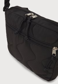 Borsa a tracolla nera trapuntata con due scomparti con zip, caratterizzata da un tessuto liscio, hardware in tonalità argento e tracolla regolabile.