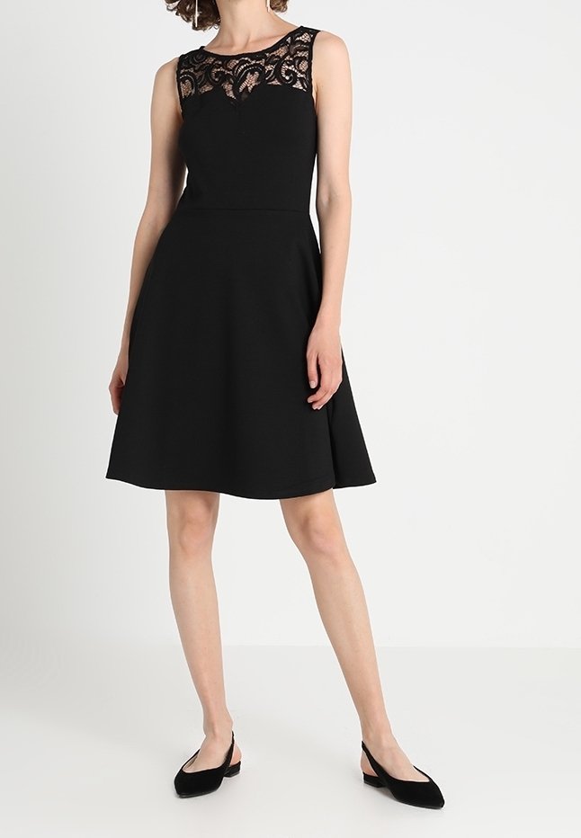 Czarna sukienka z dopasowaną górą i rozkloszowanym dołem. Posiada koronkową nakładkę przy dekolcie. Gładki materiał, bez rękawów i długość do kolan.