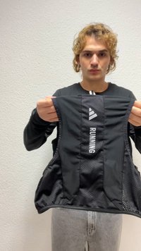 Melns skrienamais veste bez piedurknēm ar tīkliņa sānus, priekšpusē ar burtisku "RUNNING" tekstu un logotipu. Mīksts, elpojošs audums.