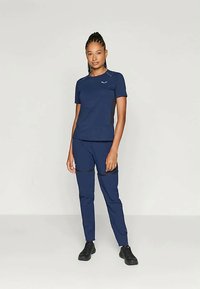 Λαχανί αθλητική ενδυμασία που περιλαμβάνει μπλούζα με κοντό μανίκι και τσάκινα παντελόνια. Το ύφασμα έχει λεία υφή με αντίθετες πλευρικές πάνελ και τσέπες με φερμουάρ.