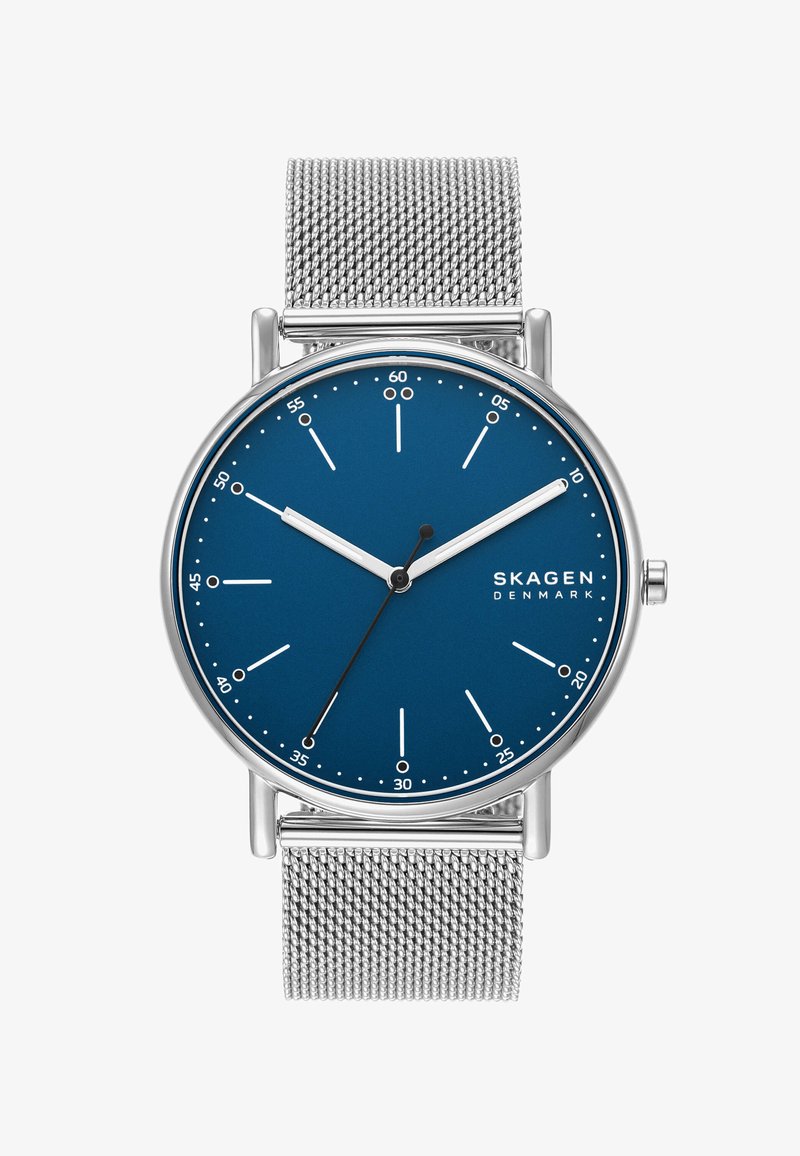 Kulaté hodinky Skagen s modrým ciferníkem, stříbrnými hodinovými značkami a nerezovým síťovaným páskem. Minimalistický design, žádné číselné značky, elegantní povrch.