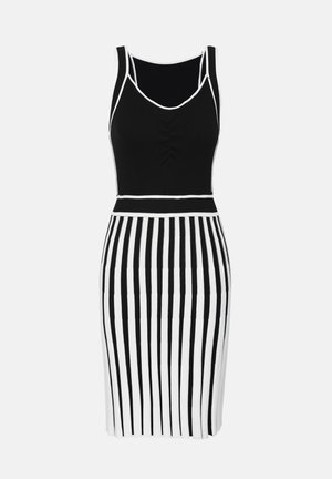 Svart og hvit stripete ermeløs kjole med tettsittende bodice, ribbet tekstur og samlet detalj ved utrigningen. Akkompagnert av hvite kanter.