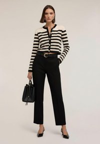 Svartvit randig kort kofta, svarta skräddarsydda byxor, blanka svarta högklackade skor, svart handväska, stilren design, knapplåsdetaljer.
