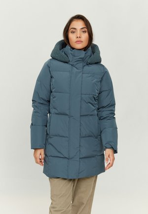 Padded türkisfarbener Jacke mit einer strukturierten Fleece-gefütterten Kapuze, ausgestattet mit einem Reißverschluss vorne und großen gesteppten Abschnitten. Kombiniert mit hellen Hosen.