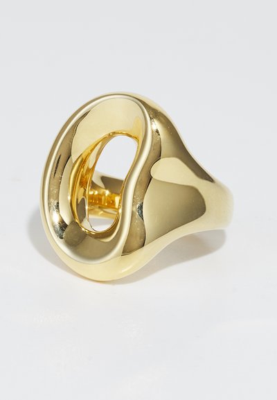 Guldring med en slät, böljande design och en ihålig mittdel, med en polerad yta som reflekterar ljus. Lämplig för olika tillfällen.
