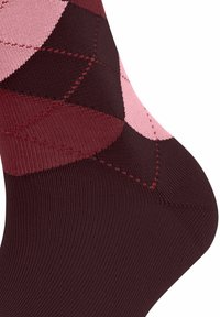 Burgundy and pink argyle-patterned socks made of textured fabric; ribbed design with contrasting colors and stitching details near the heel.