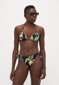 Svart bikini med tropiskt blommönster i gult och grönt. Trefaldig topp med tunn remmar, justerbara sidoknyt på botten.