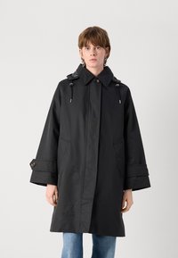 Black waterproof coat with a collar, drawstring hood, two front pockets, and wide sleeves. Features button accents and a sleek design.