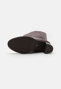 Bottine en simili cuir bordeaux avec une surface texturée, bout rond et semelle en caoutchouc noir. Dotée d'un léger talon pour plus de stabilité.