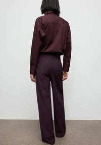 Bordeaux overhemd met lange mouwen en rugpand, gecombineerd met bijpassende wijde broek. Glad materiaal met een minimalistisch ontwerp.