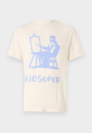 Camiseta de algodón crema con un gráfico azul de una figura sentada pintando en un caballete, con el texto "KiDSUPER" debajo en el mismo color.