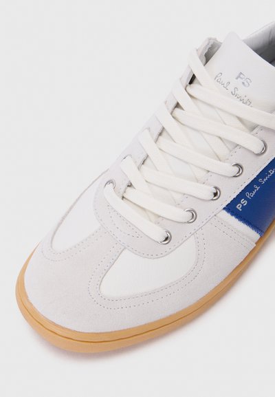 Hvite og grå sneakers laget av semsket skinn og lær. Har blå detaljer, rund tå, flat gummisåle og flere snorlommer med lisser.