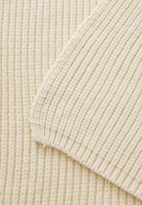 Off-white ribbet tekstil, der fremviser en blød, struktureret overflade med tydelige lodrette linjer og en let fuzzy finish.