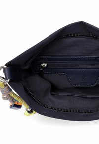 Wnętrze granatowej torby materiałowej z kieszenią na zamek, gładką teksturą i detalem z logo. Posiada kolorowe ozdobne elementy mocowane do paska.