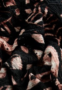 Svart och rosa mönstrad tyg med en texturerad yta, som har virvlar och utskurna detaljer i en mjuk, draperad arrangemang.