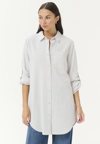 Light blue and white striped long-sleeve shirt with a collar, button front, and single chest pocket. Rolled sleeves with button tabs.