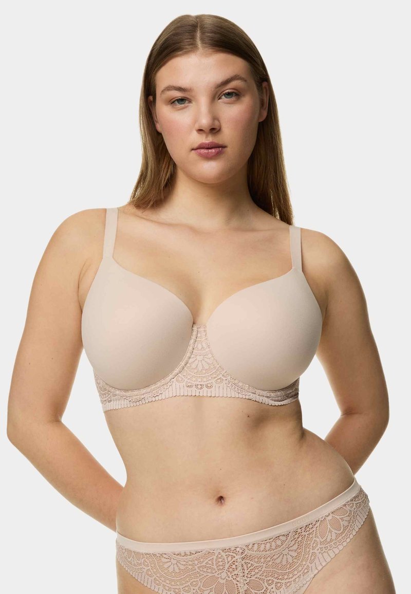 Reggiseno senza coppe con coppe lisce, bordo in pizzo e spalline regolabili. Presenta un design senza cuciture e un motivo floreale lungo la bande.