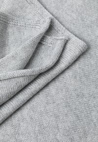 Grijze gebreide stof met een zachte textuur, met een licht gemêleerd patroon en gevouwen randen, die dikte en warmte uitstralen.