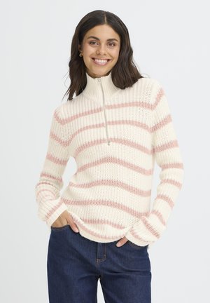 Pull à rayures crème et rose avec un col montant, fermeture éclair et texture côtelée. Les manches sont longues et l'ourlet est légèrement courbé.