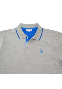 Polo gris avec un col bleu et une patte de boutonnage. Présente un logo brodé bleu sur la poitrine. Fabriqué en tissu doux et texturé.