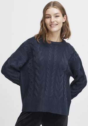 Pull en maille torsadée bleu marine avec un col rond, un ourlet côtelé et des motifs texturés sur les manches et le corps, fabriqué à partir d'un tissu doux et texturé.