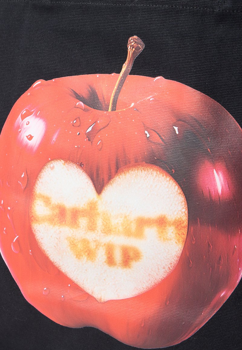 Roter Apfel mit Wassertropfen und einem herzförmigen Biss, der unscharfen Text im Inneren zeigt, vor einem schwarzen Hintergrund.