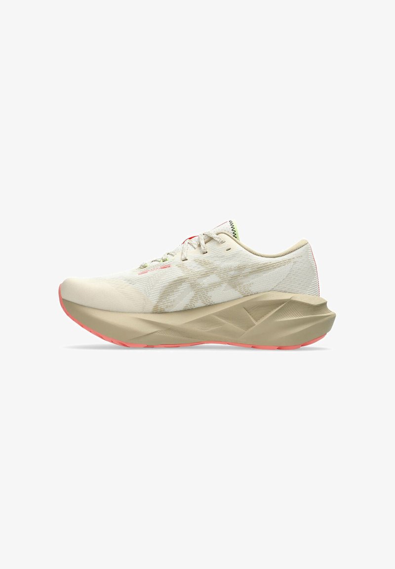 Zapatilla de running beige con un upper texturizado, que presenta un patrón en gris claro, una lengüeta acolchada y una suela rosa con detalles de diseño esculpidos.