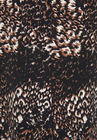 Djurmönstrad tyg med en blandning av svarta, bruna och vita nyanser. Designen inkluderar abstrakta leopardliknande former och texturer.