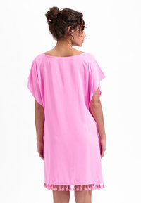 Roze kaftan met een losse pasvorm, korte mouwen en een zoom versierd met franjes. Gemaakt van zachte stof met een gladde textuur.