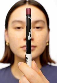 Lipcrayon in donker bordeaux met een zwart-wit ontwerp. De dop is afgerond, terwijl het lichaam het merk "All Tigers" toont.