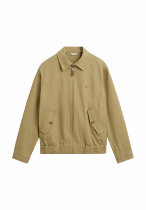 Chaqueta ligera de color beige con cuello tipo camisa, cierre frontal y dos bolsillos de parche. Cuenta con una cinturilla elástica y un discreto detalle de logo.