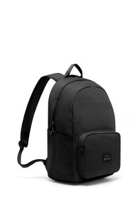 Svart tyg ryggsäck med rundad topp, framficka med dragkedja, justerbara axelremmar och en liten logotyp-patch på framfickan.