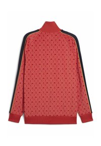 Chaqueta roja con cremallera y un patrón texturizado, con un cuello alto y mangas negras en contraste con franjas doradas. Puños y dobladillo acanalados.