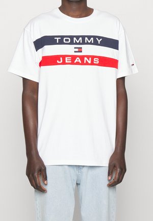 Biała bawełniana koszulka z granatowymi i czerwonymi poziomymi paskami. Z nadrukiem "TOMMY" i "JEANS" w wyraźnych czarnych literach. Luźny krój, krótkie rękawy.