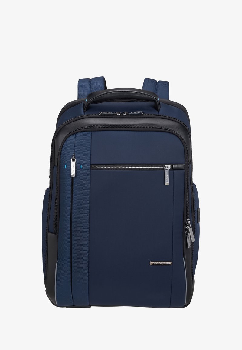 Zaino blu navy con dettagli neri, tessuto testurizzato, spallacci regolabili doppi, maniglia superiore e molteplici scomparti con zip.
