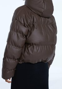 Giubbotto puffer marrone con cappuccio, dotato di una finitura lucida, design trapuntato, orlo elasticizzato e tasche laterali con zip.
