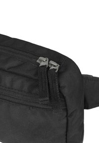 Černá látková taška se dvěma šedými zipy, s texturovaným povrchem a zesíleným švem podél okrajů. Kompaktní a elegantní design.