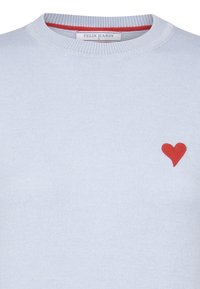 Pull léger bleu avec une texture côtelée, arborant un petit cœur rouge brodé sur la poitrine gauche et un col intérieur rouge contrastant.