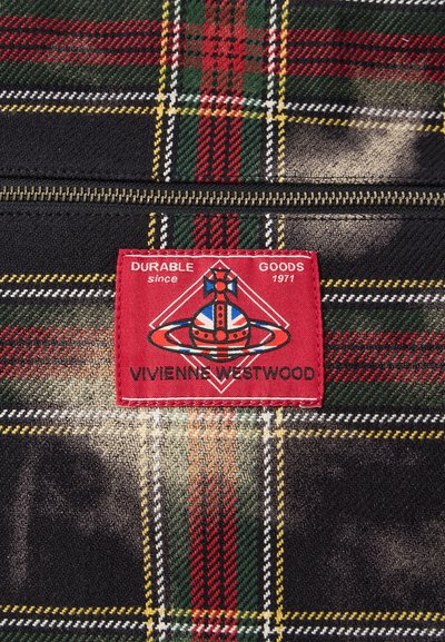 Károvaná tkanina s červenými, zelenými, žltými a bielymi vzormi. Pripojená červená etiketa s logom a textom "DURABLE GOODS 1971 VIVIENNE WESTWOOD". Viditeľný zips.