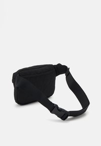Bolso bandolera negro acolchado con forma rectangular, cuenta con una correa ajustable y un cierre de hebilla lateral. Detalle de superficie texturizada.