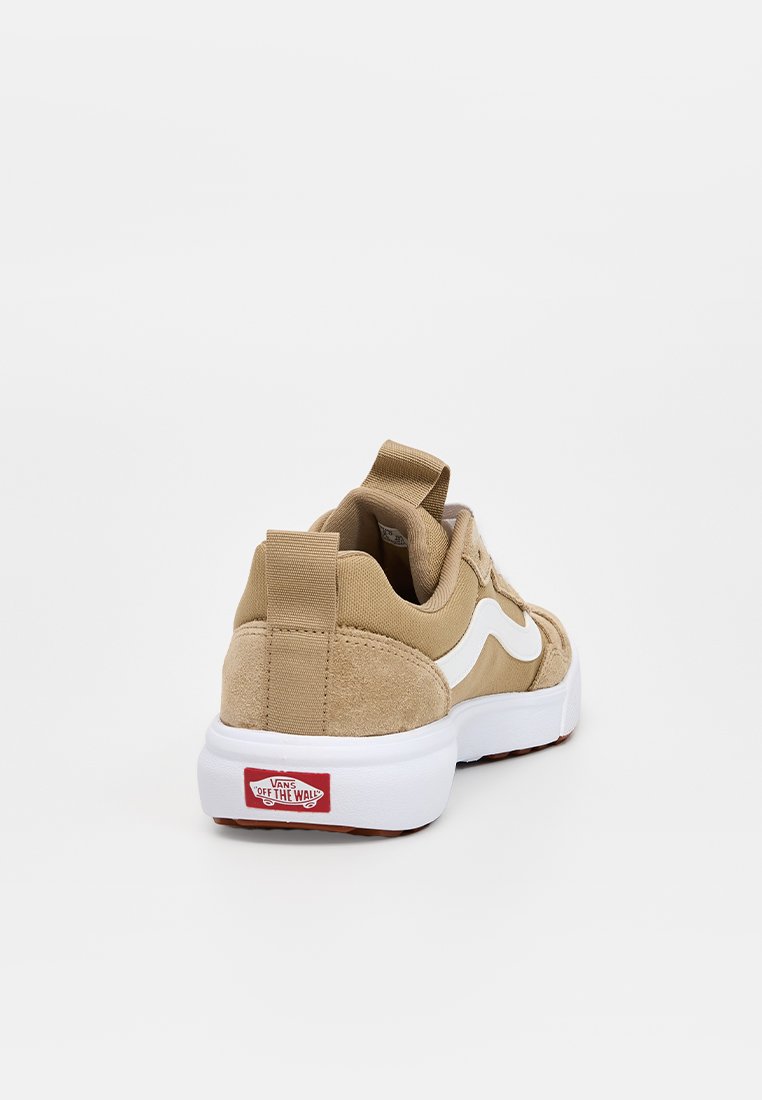 Zapatillas beige que combinan materiales de ante y lona, con un diseño de ola blanca como acento y una suela de goma blanca con marca roja.