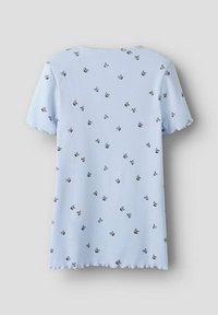 Lyseblå ribbet kortærmet top med en bølget kant, prydet med sort blomsterdesign spredt over stoffet.