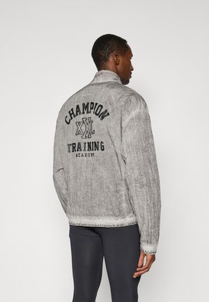 Gray bomber jacket with elastic cuffs and hem. Large "Champion" and "Training Academy" printed on the back in black. Textured fabric.