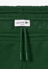 Gröna slim-fit sweatpants med dragsko i midjan, mjuk textur och Lacoste-logotag med krokodil-emblem.