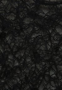 Material din dantelă neagră, cu modele florale complicate și un aspect delicat și texturat, având variații în transparență pe tot parcursul designului.