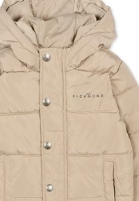 Giacca puffer beige con cappuccio, dotata di bottoni a pressione argentati, texture trapuntata e stampa del logo sul lato sinistro.